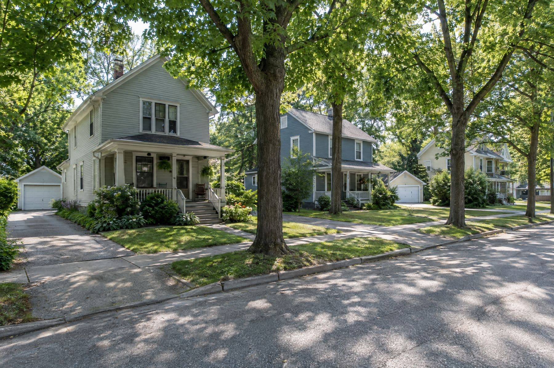 A tree-lined street of older homes with detached garages