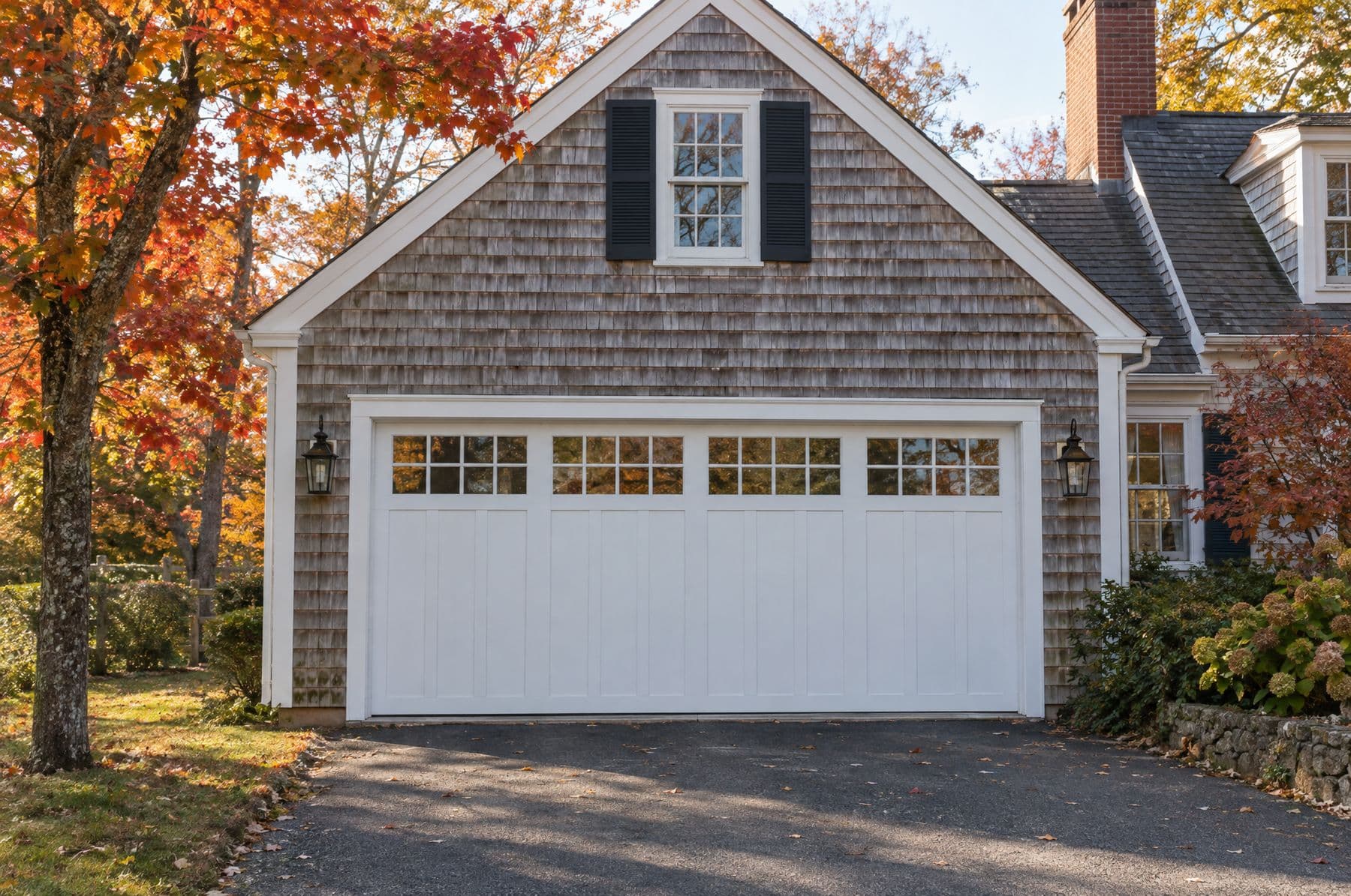 A white long-panel garage door with a window row on a shingle cape