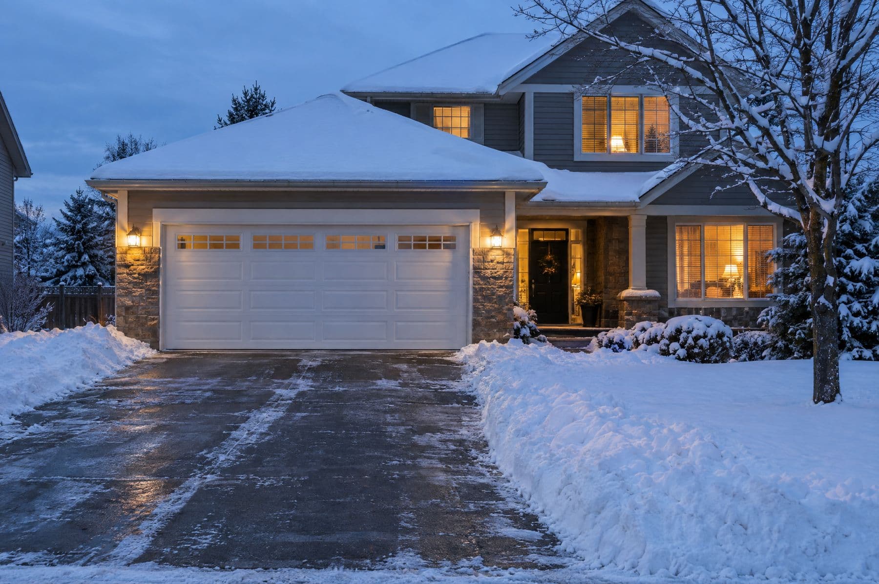 A white insulated garage door on a snowy evening